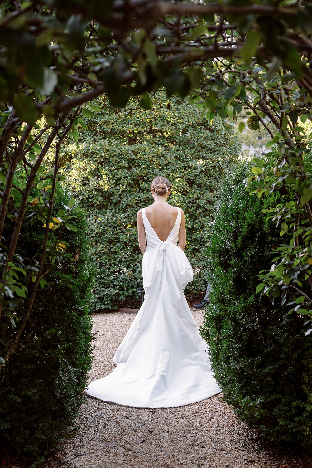 Image of back of bride's dress framed by the gardens of The WIlliam Paca House.