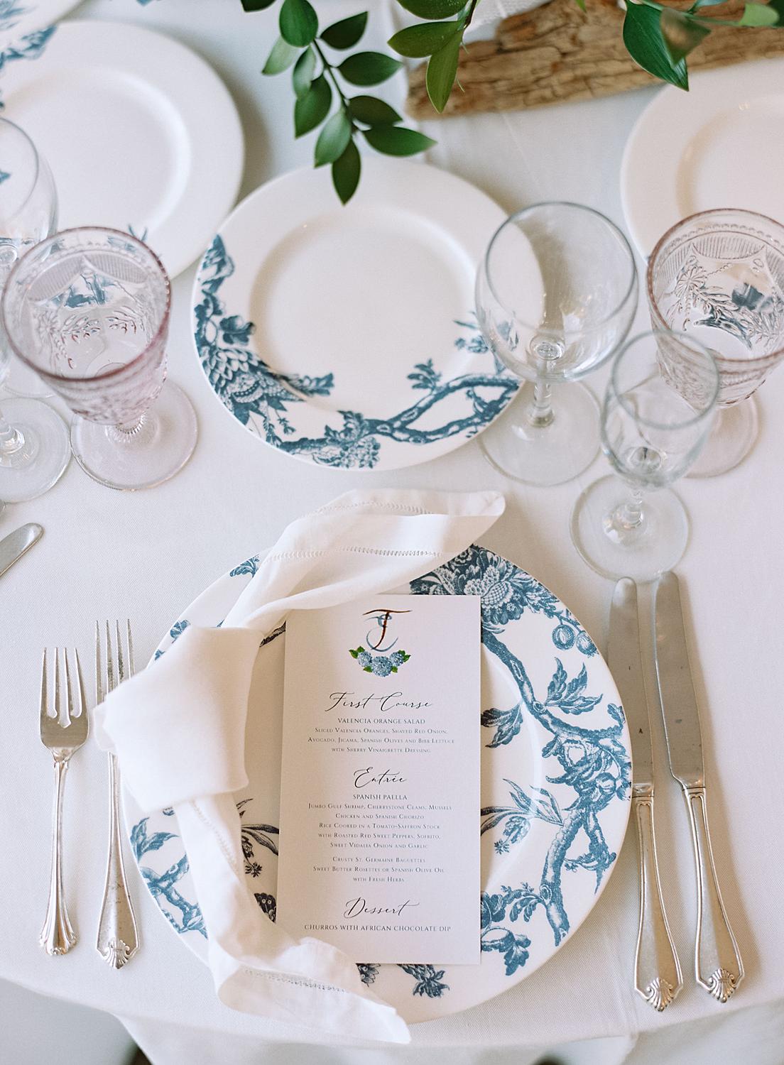 Detail shot of the wedding reception table details. Chinoiserie plate, colored water glasses and colorful centerpiece florals at William Paca House.