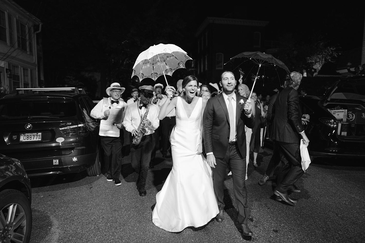 Bride and groom walking out of their William Paca House wedding with marching band as they walk down the street.